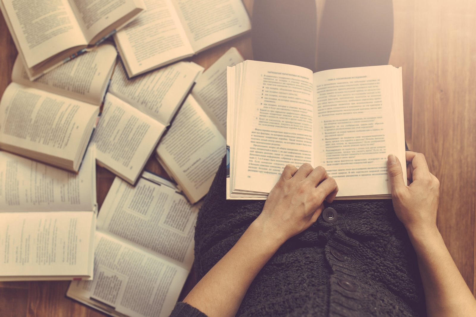 woman reading a few books on the floor